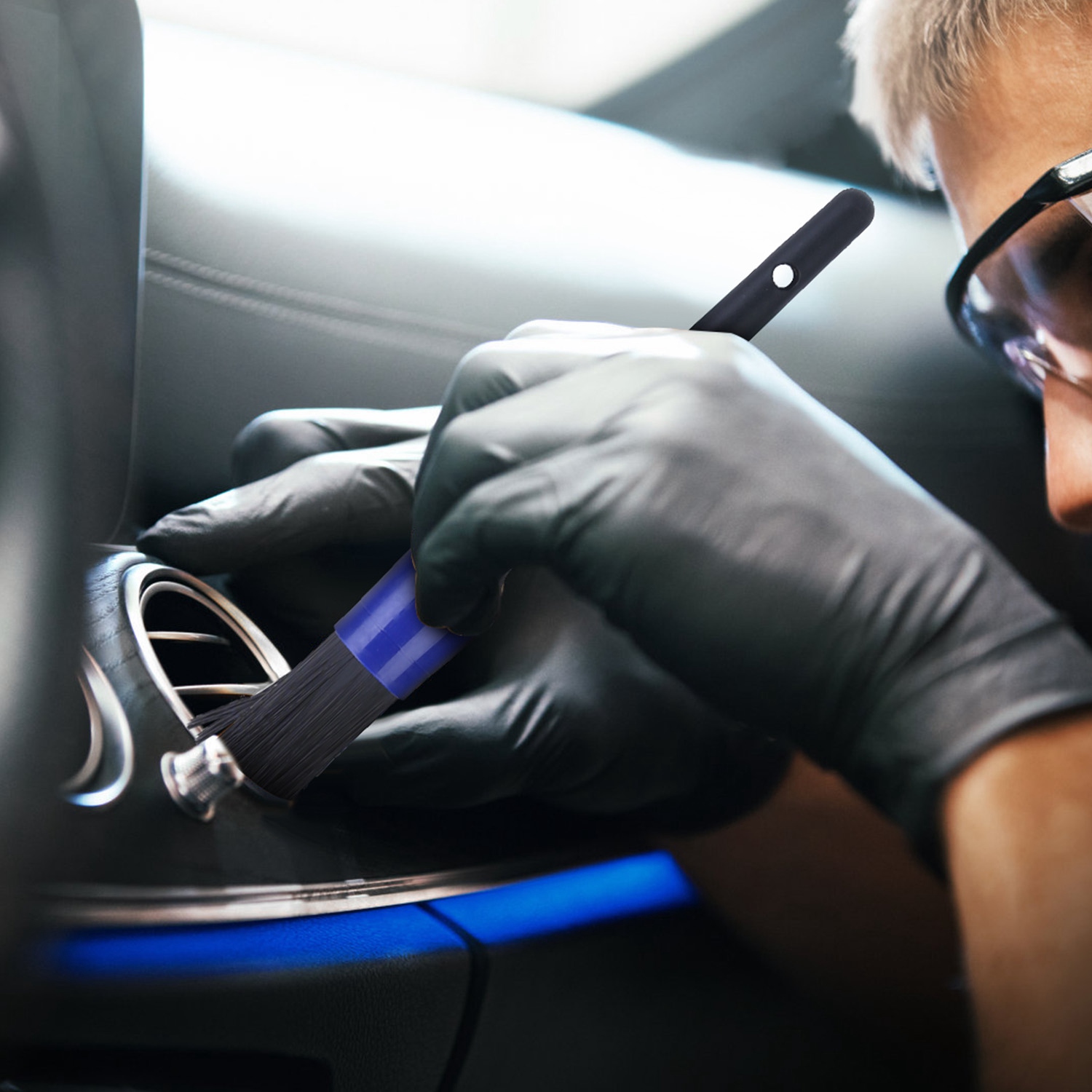 Detailing brush cleaning an air vent inside a car